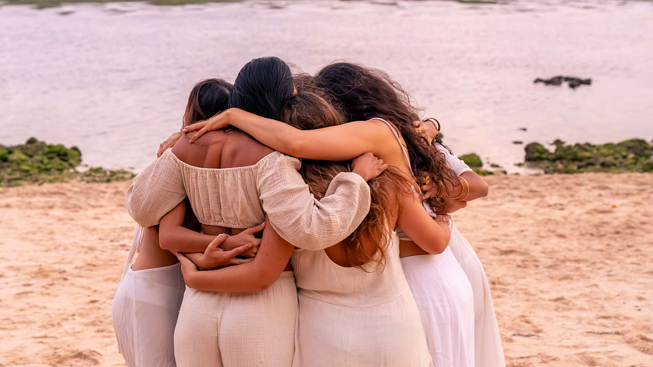 Mujeres abrazadas en círculo en la playa