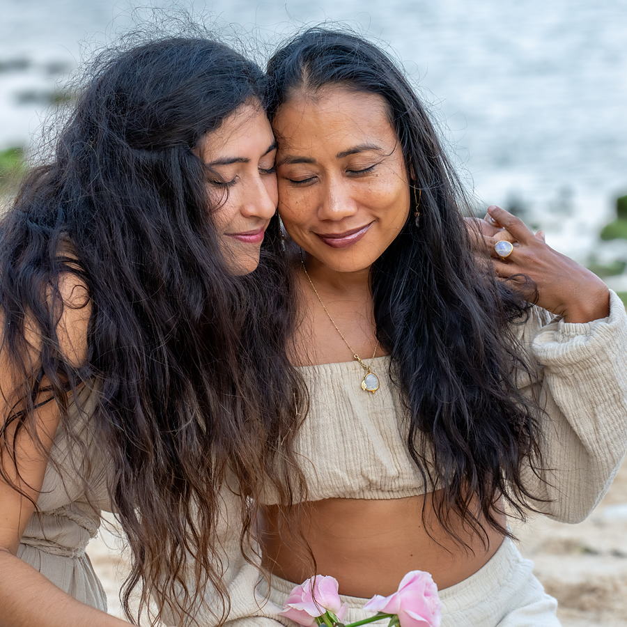 Dos mujeres abrazadas, con los ojos cerrados, frente al mar
