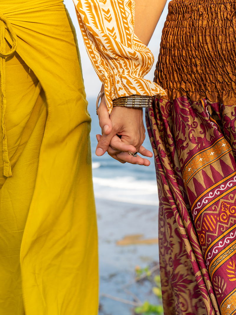 Dos mujeres tomadas de la mano frente al mar